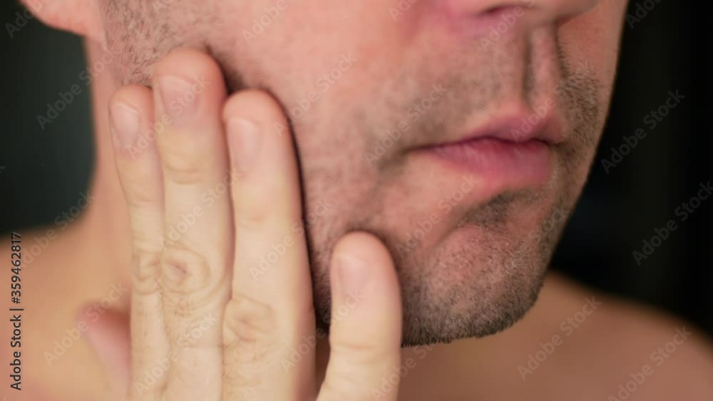 Man examines his unshaven face close up and plans to shave his bristles Man examines his unshaven face close up and plans to shave his bristles