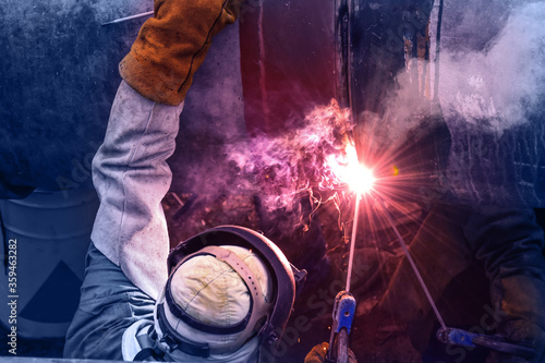 Workers with protective masks welding bore pile metal casing at a construction site. © Hor