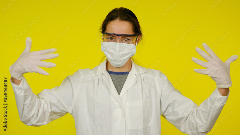 Young doctor in protective medical mask, glasses and latex gloves. Nurse in a white coat on a yellow background Young doctor in protective medical mask, glasses and latex gloves. Nurse in a white coat on a yellow background