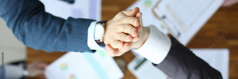 Top view of co-workers giving high five in company office. Business people on meeting in conference room. Greeting gesture. Team work and communication concept
