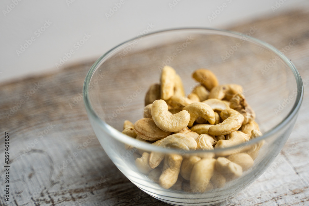 Cashew nuts in a small plate on a vintage wooden table as a background. Cashew nut is a healthy vegetarian protein nutritious food. Cashew nuts in a small plate on a vintage wooden table as a background. Cashew nut is a healthy vegetarian protein nutritious food.