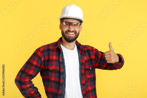 Handsome bearded engineer or constructor man in casual outfit show good gesture over yellow background. photo