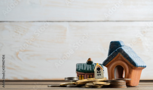 miniature house model with coins on wood background 