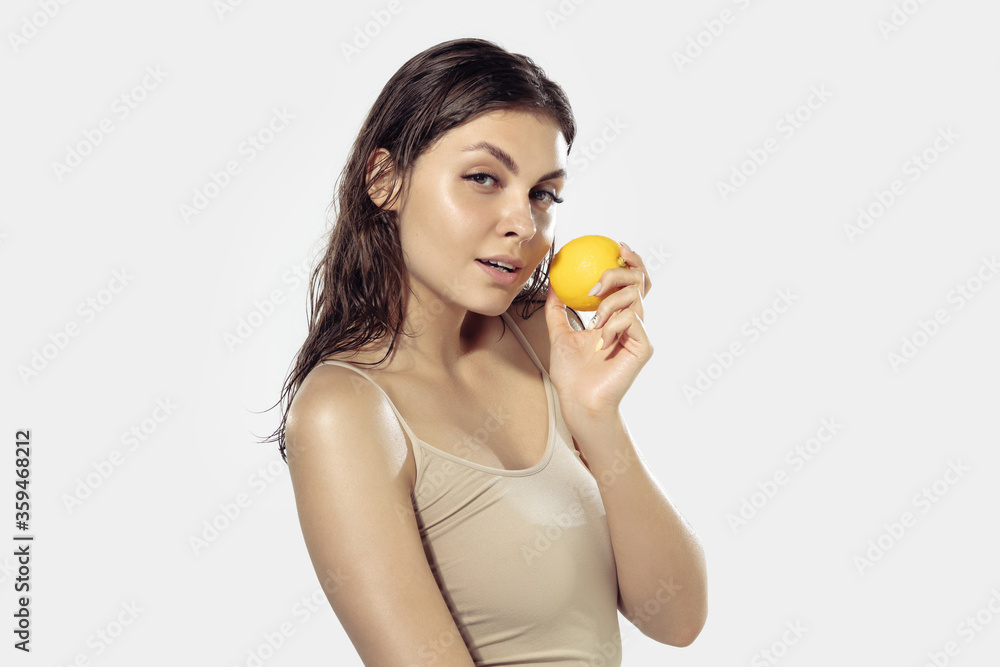 Shiny. Beautiful young woman with fresh lemon near face on white background. Concept of cosmetics, makeup, natural and eco treatment, skin care. Shiny and healthy skin, fashion, healthcare. Shiny. Beautiful young woman with fresh lemon near face on white background. Concept of cosmetics, makeup, natural and eco treatment, skin care. Shiny and healthy skin, fashion, healthcare.