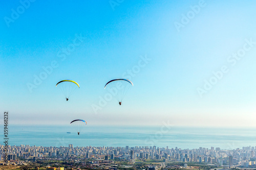 Fototapeta Naklejka Na Ścianę i Meble -  Landscape city, Mediterranean Sea and paragliding above the city. Three paragliders are flying together in Mersin, Turkey.