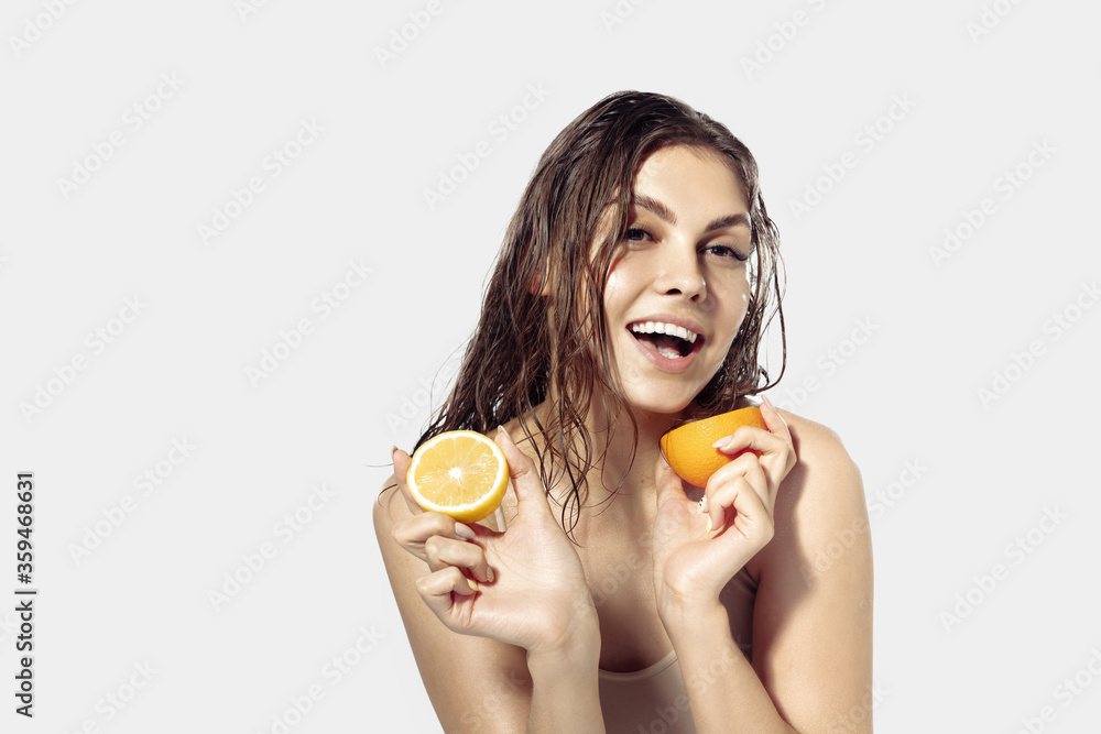 Taste. Beautiful young woman with citrus slices near face on white background. Concept of cosmetics, makeup, natural and eco treatment, skin care. Shiny and healthy skin, fashion, healthcare. Taste. Beautiful young woman with citrus slices near face on white background. Concept of cosmetics, makeup, natural and eco treatment, skin care. Shiny and healthy skin, fashion, healthcare.