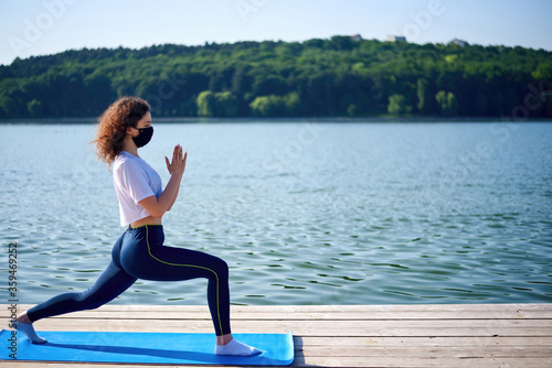 A young woman in medical mask doing yoga