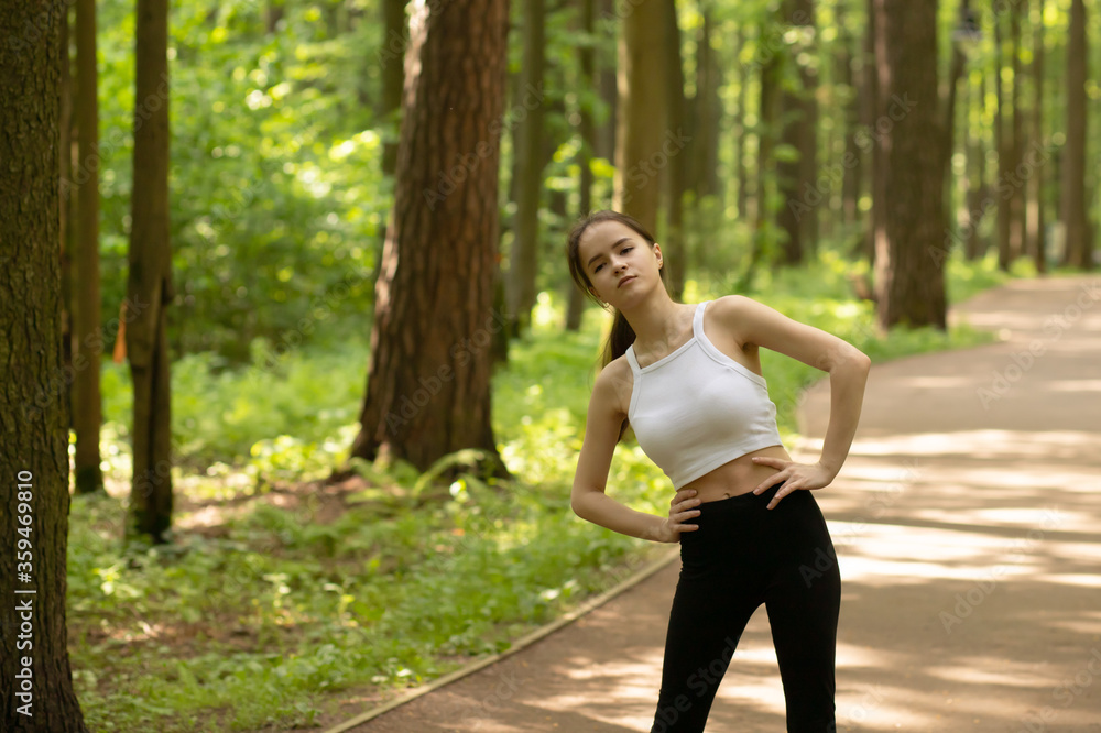 A beautiful and healthy body. Girl warming up in the park before jogging, doing exercises in nature A beautiful and healthy body. Girl warming up in the park before jogging, doing exercises in nature
