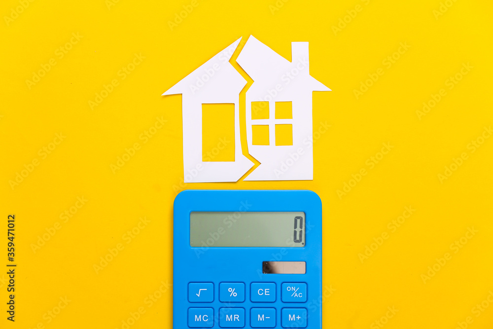 Divorce, property division concept. Split paper house and calculator on yellow background Divorce, property division concept. Split paper house and calculator on yellow background