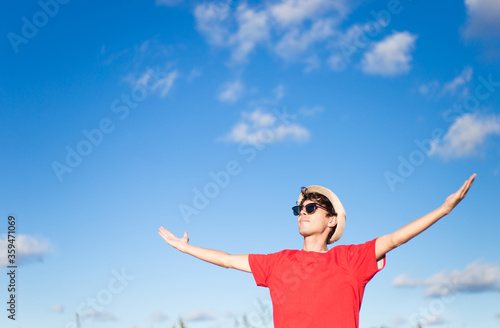 Tourist feeling free. Happy young man with arms raised with blue sky in the background. 