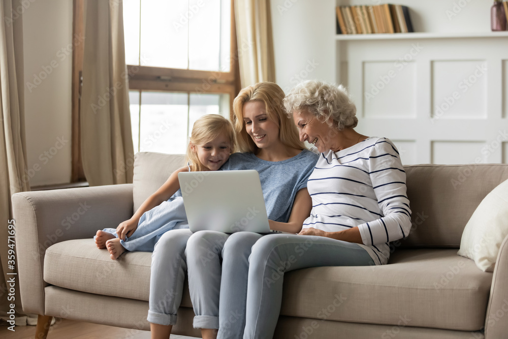 Old granny young mom little girl 3 generations women family have fun with pc, watch cartoons, use educational app for kid, choose goods, planning common vacation travel tickets hotel booking concept