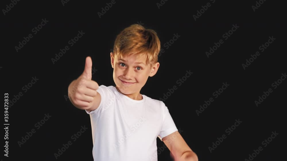 Like gesture. Support encouragement. Cheerful boy showing thumb up isolated on black background. Like gesture. Support encouragement. Cheerful boy showing thumb up isolated on black background.