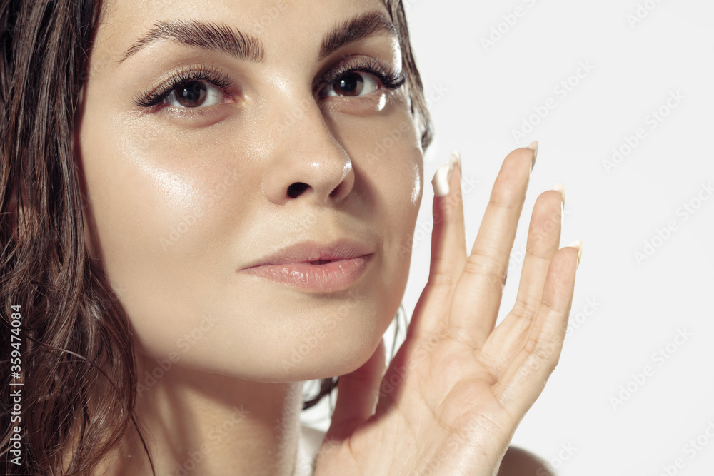 Close up beautiful young woman applying moisturizer, creme on white background. Concept of cosmetics, makeup, natural and eco treatment, skin care. Shiny and healthy skin, fashion, healthcare. Close up beautiful young woman applying moisturizer, creme on white background. Concept of cosmetics, makeup, natural and eco treatment, skin care. Shiny and healthy skin, fashion, healthcare.