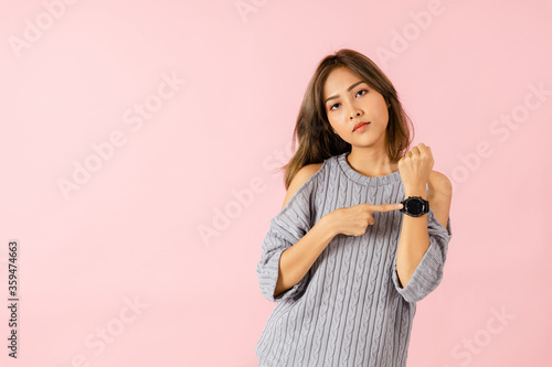фотографія Portrait of an Asian women pointing at a wristwatch. She is angry