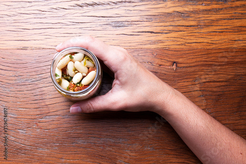 Nutrition concept - hand holds a healthy meal in glass jars over wooden background. Healthy food, Diet, Detox, Clean Eating or Vegetarian concept