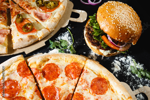 Pizza and burger on a black background. Top view.