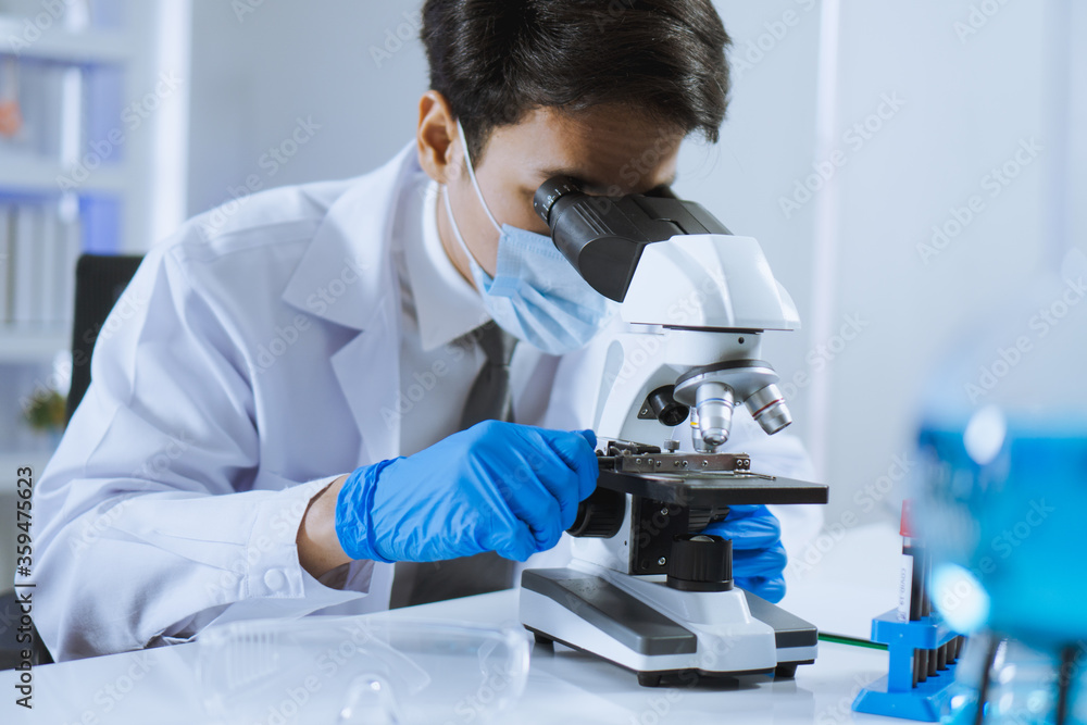 Young Asian handsome man scientist adjust focus and use Microscope to looking biochemical cell in laboratory. Doctor and scientist work in laboratory pandemic of corona virus, COVID19 concept Young Asian handsome man scientist adjust focus and use Microscope to looking biochemical cell in laboratory. Doctor and scientist work in laboratory pandemic of corona virus, COVID19 concept