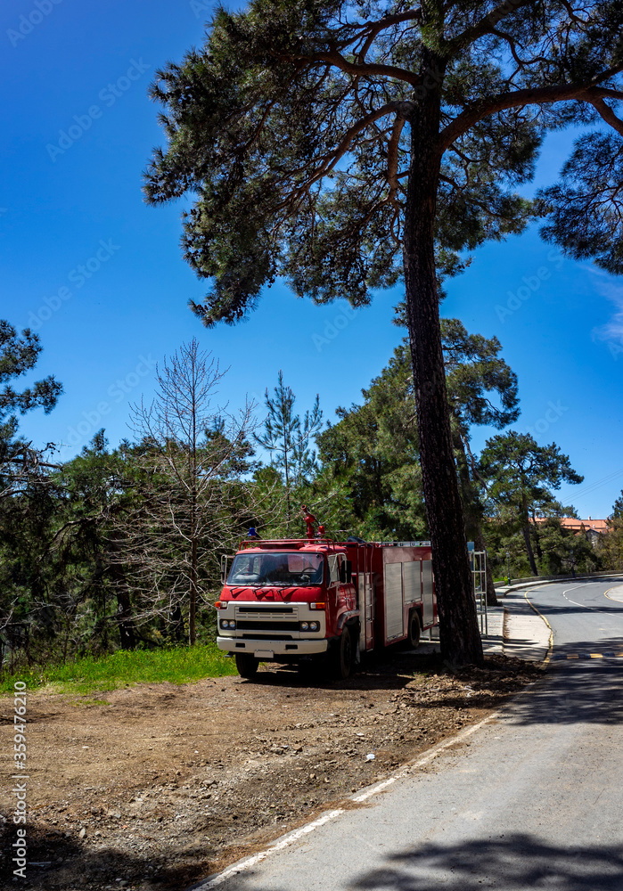 Red fire truck on a forest mountain road in the hot summer in the mountains of Central Cyprus.