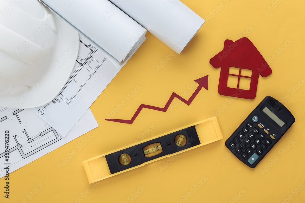 Construction helmet, blueprint, house, engineering construction supplies and growth arrow tending upwards on a yellow background. Top view