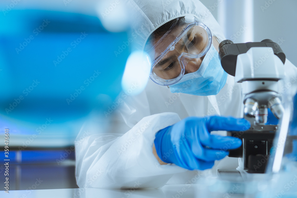 Young Asian handsome man scientist adjust focus and use Microscope to looking biochemical cell in laboratory. Doctor and scientist work in laboratory pandemic of corona virus, COVID19 concept Young Asian handsome man scientist adjust focus and use Microscope to looking biochemical cell in laboratory. Doctor and scientist work in laboratory pandemic of corona virus, COVID19 concept