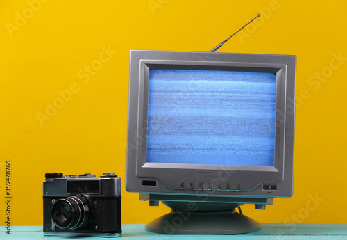 Antenna old-fashioned retro tv receiver with film camera on yellow background. Retro entertainment 80s