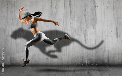 Sporty young woman running on wall background