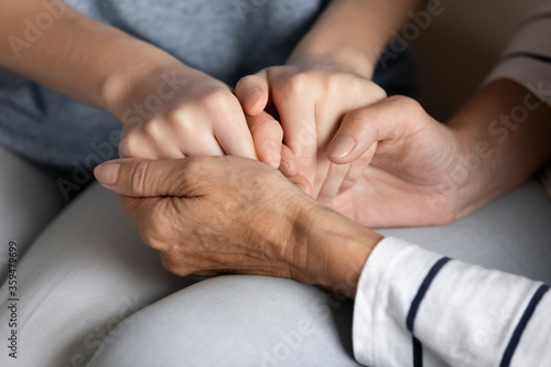 Close up elderly loving caring mother holding hands of grown up adult teenager daughter share pain, relieving heartbreak first unrequited feelings, provide psychological support with deep love concept