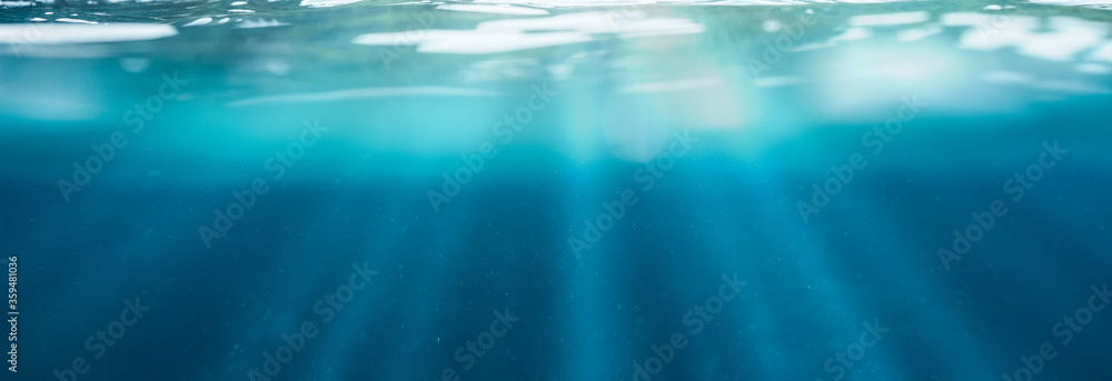 Blue underwater with sunlight shining through water surface in tropical sea