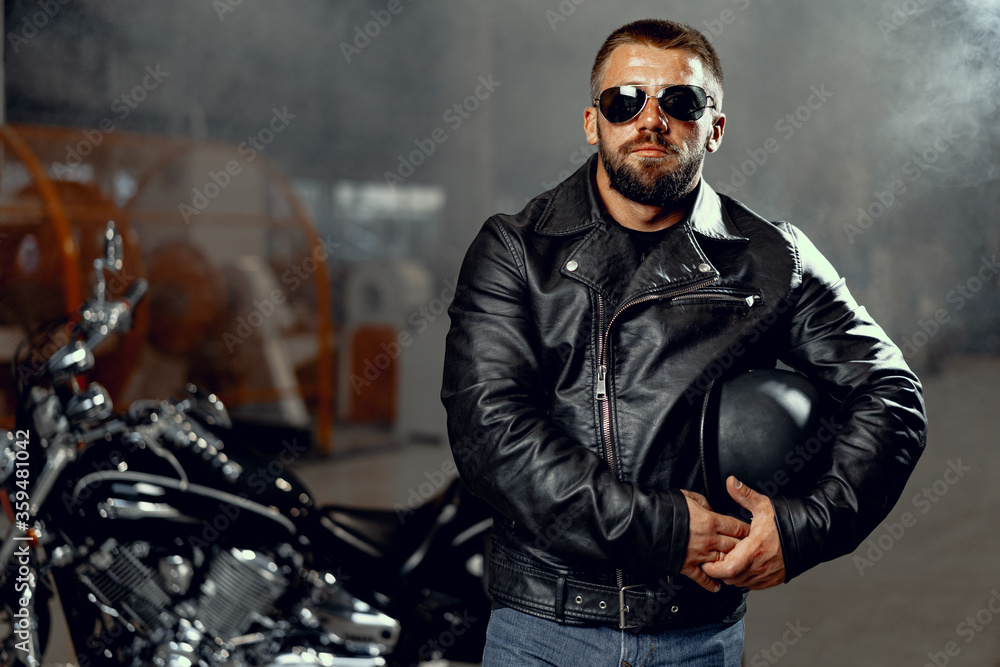 Portrait of bearded man motocyclist in dark sunglasses on dark background Portrait of bearded man motocyclist in dark sunglasses on dark background