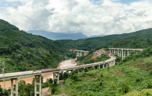 Belt and Road Initiative, One Belt One Road (OBOR) corporate - Chinese Xiaomo Highway bridge under construction in the green jungle between Lao border town Boten and Mengla, Yunnan, China