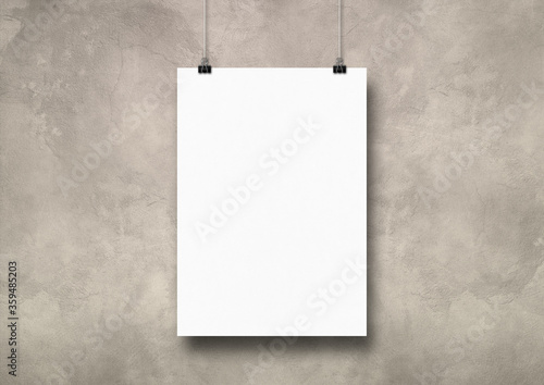 White poster hanging on a light concrete wall with clips
