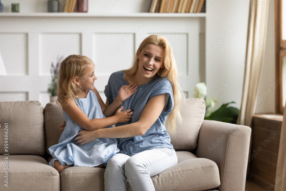 Mother play active games tickling little daughter family laughing spend funny weekend time sit on couch. Nanny and kid girl activity at home, happy motherhood next generation relation and love concept Mother play active games tickling little daughter family laughing spend funny weekend time sit on couch. Nanny and kid girl activity at home, happy motherhood next generation relation and love concept
