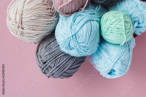  Women's hobby. Crochet and knitting. Multicolored skeins of yarn in the basket on a pink background. Studio shooting.