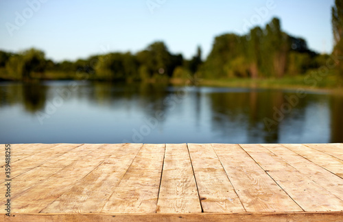 Mockup. Empty wooden deck table with foliage bokeh background.