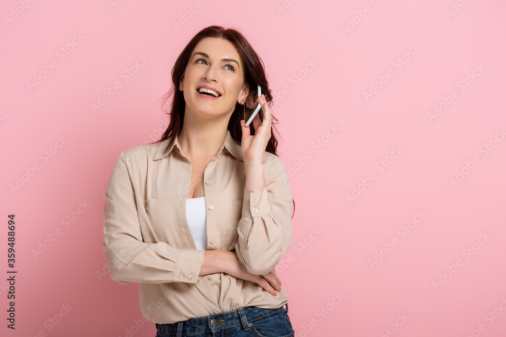 Beautiful smiling woman talking on smartphone on pink background Beautiful smiling woman talking on smartphone on pink background