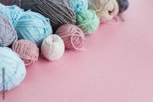 Women's hobby. Crochet and knitting. Multicolored skeins of yarn in the basket on a pink background. Studio shooting. 