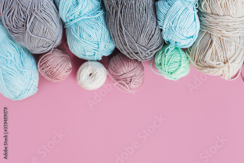 Women's hobby. Crochet and knitting. Multicolored skeins of yarn in the basket on a pink background. Studio shooting. 