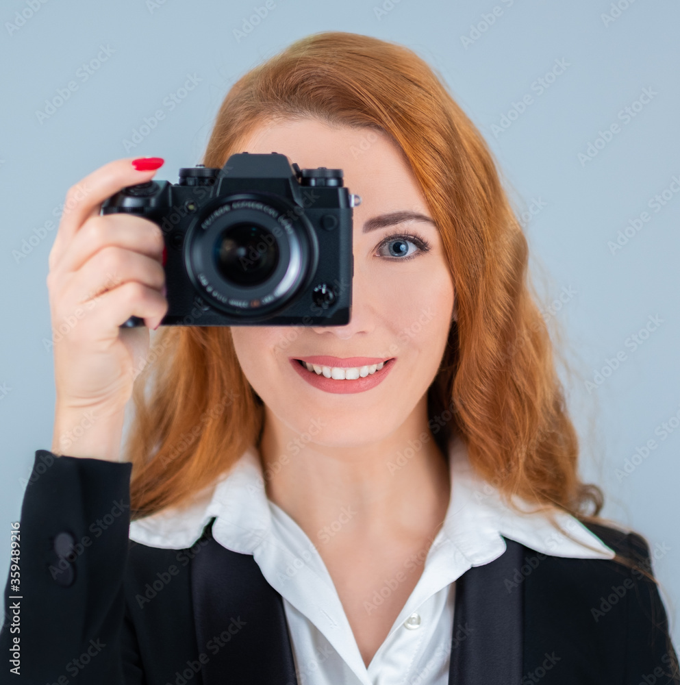 Young redhead woman holding a camera. She is wearing a suit. Young redhead woman holding a camera. She is wearing a suit.