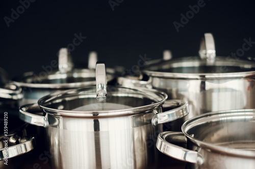 Set of kitchen metallic pans standing on wooden countertop on dark background