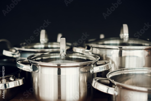 Set of kitchen metallic pans standing on wooden countertop on dark background