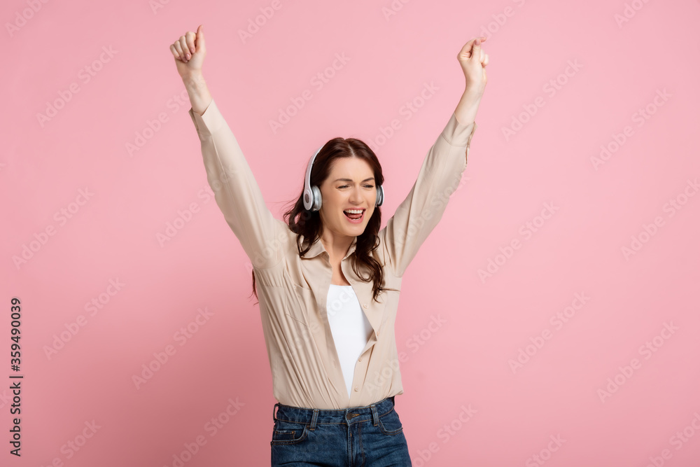Beautiful happy woman dancing in headphones on pink background, concept of body positive Beautiful happy woman dancing in headphones on pink background, concept of body positive