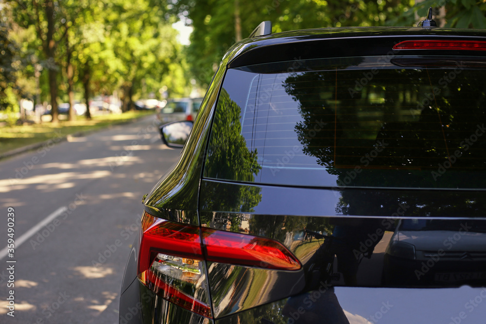 Back window of black car parked on the street in summer sunny day, rear view. Mockup for