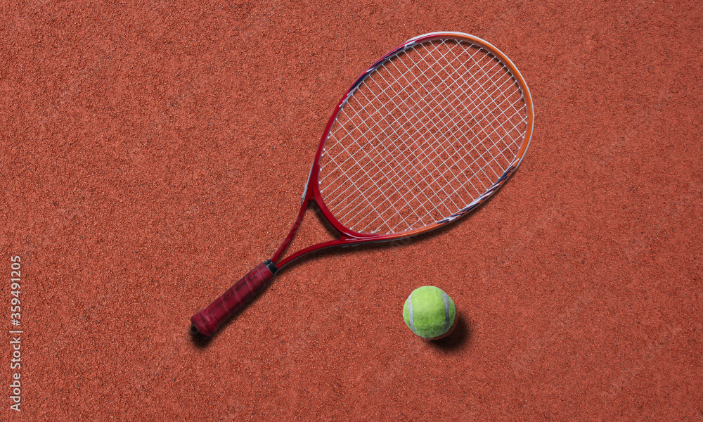 Tennis racket and ball on red court