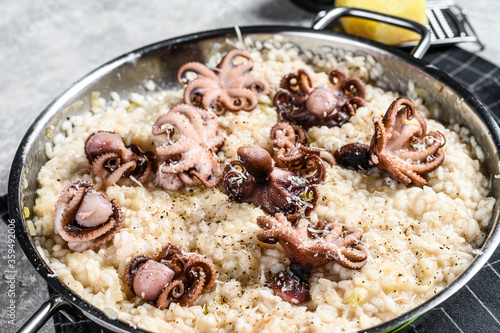Italian Risotto with octopus and mushrooms decorated with Parmesan and parsley. Gray background. Top view