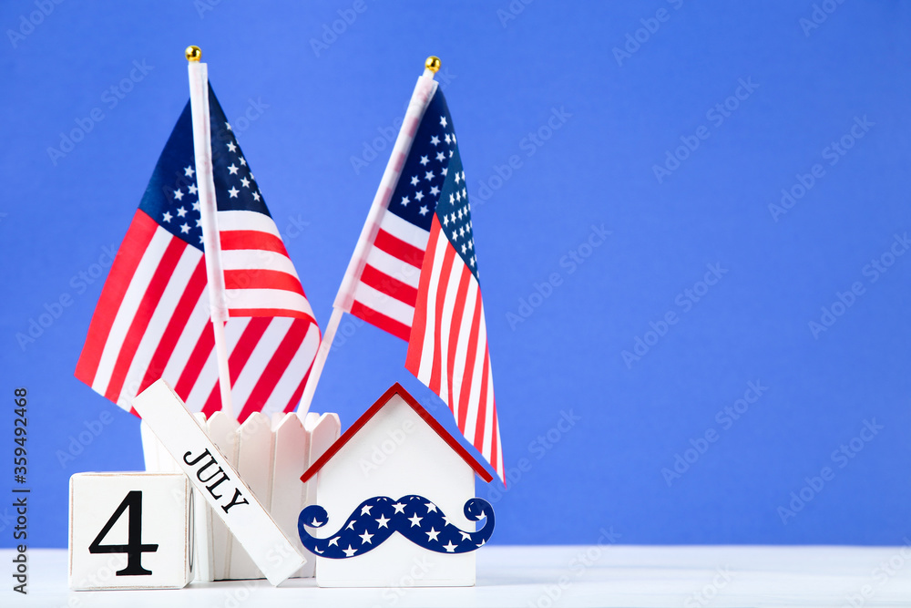 Independence Day concept. American flags with cube calendar and house model on blue background