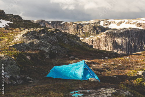 Tourist's tent stands in the mountains. Summer sunrise above beautiful rocks in Norway.