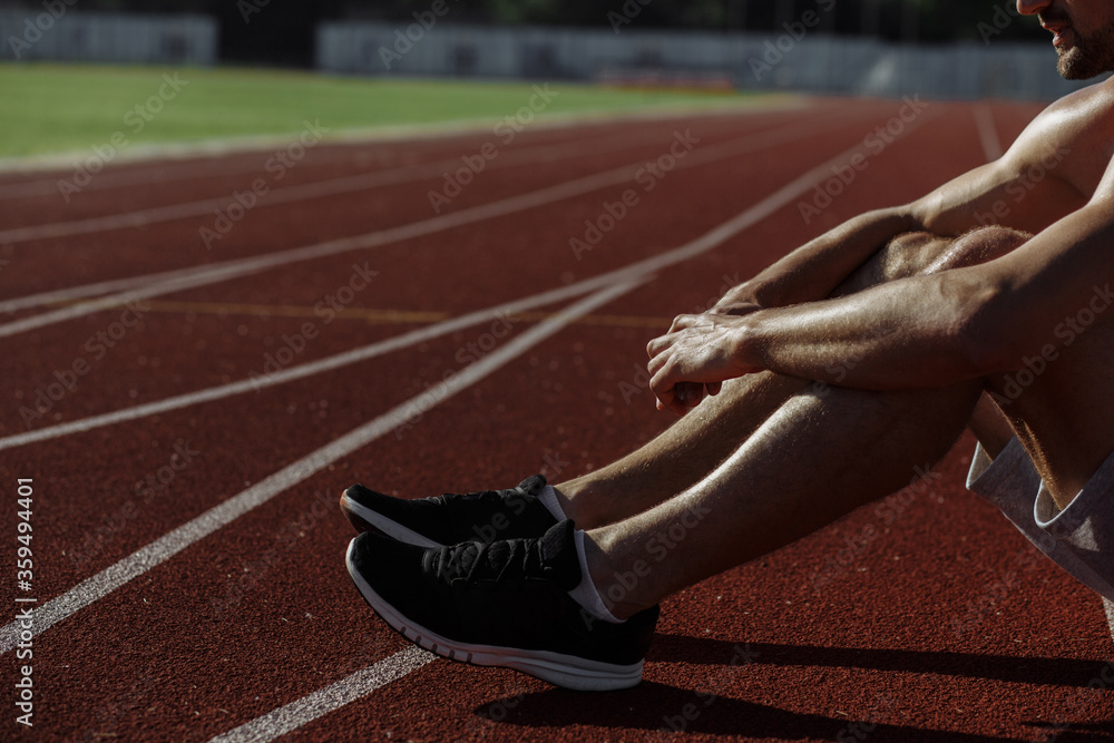Man's legs. Atlete sitting on the track. Sportsman. Strong man