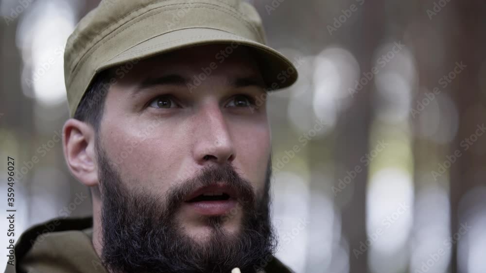 Portrait of handsome young man hunter blows in decoy and beckons wildfowl. Man in camouflage clothes hunts outdoor in forest hunting alone. Close up of man hiker standing in forest. Portrait of handsome young man hunter blows in decoy and beckons wildfowl. Man in camouflage clothes hunts outdoor in forest hunting alone. Close up of man hiker standing in forest.