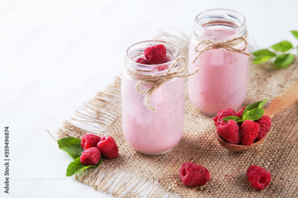 Raspberry smoothie in glass jars and spoon on white wooden table Raspberry smoothie in glass jars and spoon on white wooden table