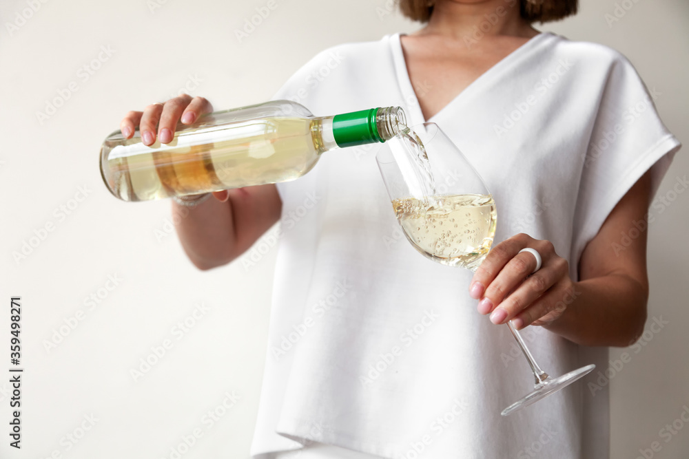 Female hands pour white wine from bottle to glass Female hands pour white wine from bottle to glass